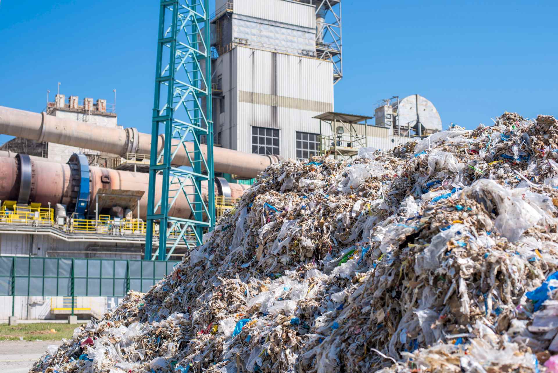 Shredded municipal waste used as alternative fuel and rotary cement kiln in the background